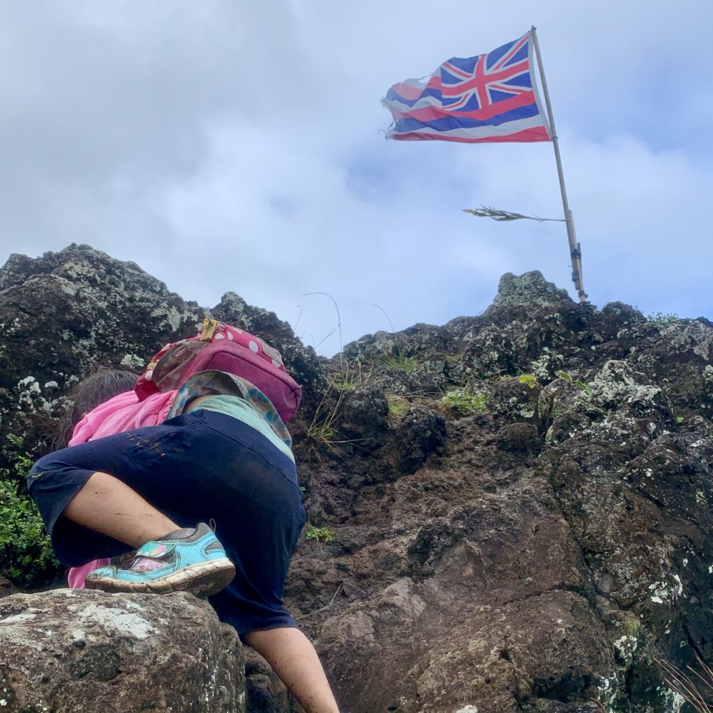 ハワイ国旗のある山を登る娘