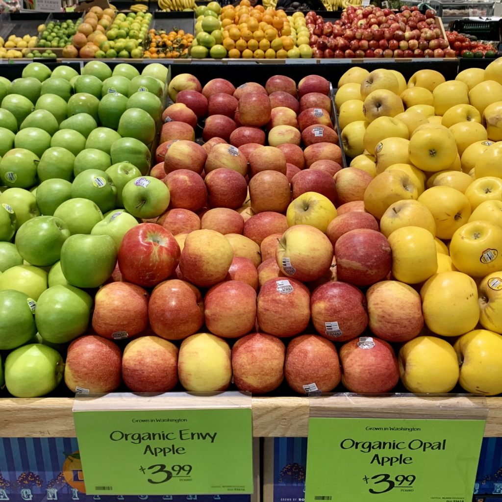 緑、赤、黄のりんごがきれいに陳列されている